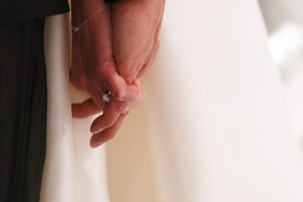 Close-up of the bride and groom holding hands, showing the wedding rings